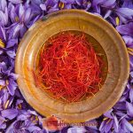 An earthen plate filled with saffron filaments, in the middle of the flowers